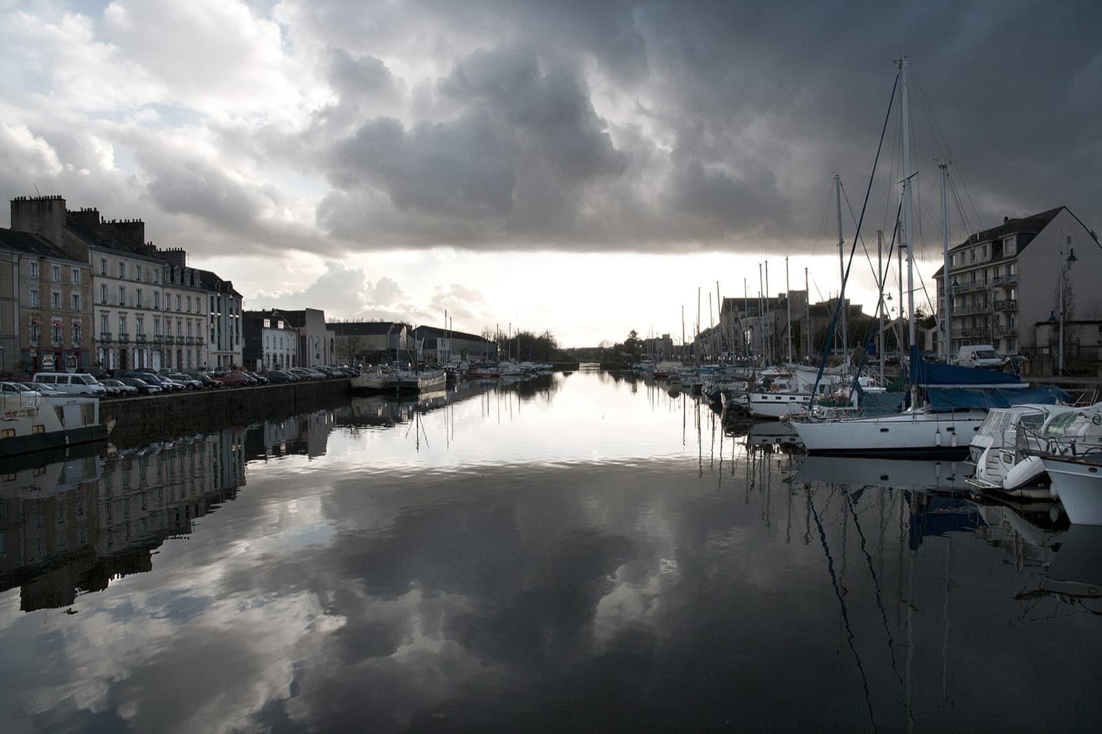 Le port de Redon, quai Surcouf, avec des voiliers amarrés et les façades du quai qui se reflètent dans l’eau